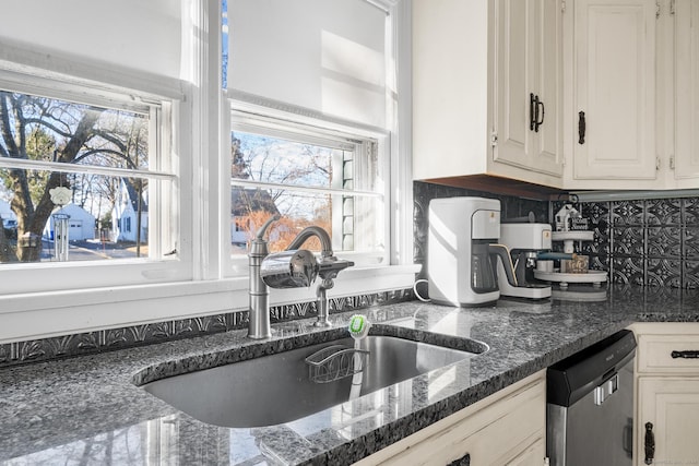 kitchen featuring dishwasher, sink, backsplash, dark stone countertops, and white cabinets