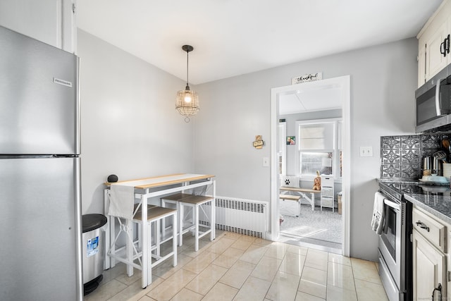 kitchen featuring white cabinetry, radiator heating unit, stainless steel appliances, pendant lighting, and light tile patterned floors