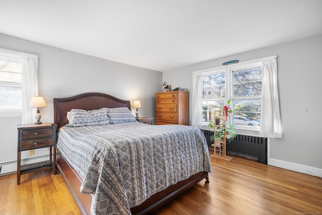 bedroom with hardwood / wood-style floors, radiator heating unit, and baseboard heating