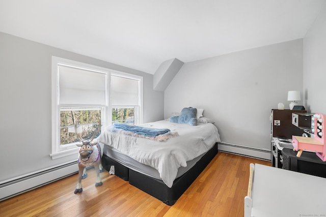 bedroom with a baseboard radiator, hardwood / wood-style flooring, and lofted ceiling