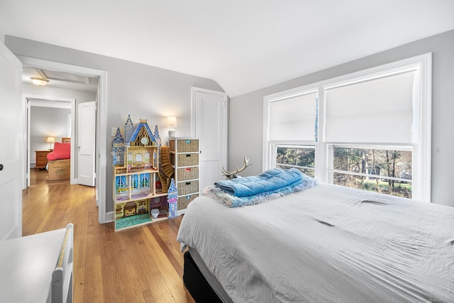 bedroom with light hardwood / wood-style floors and lofted ceiling