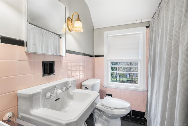 bathroom featuring tile patterned floors, toilet, tile walls, and sink