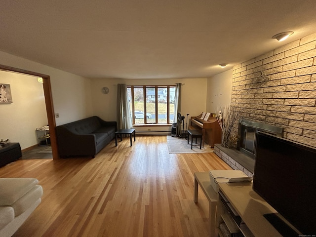 living room featuring light hardwood / wood-style floors, a brick fireplace, and a baseboard radiator