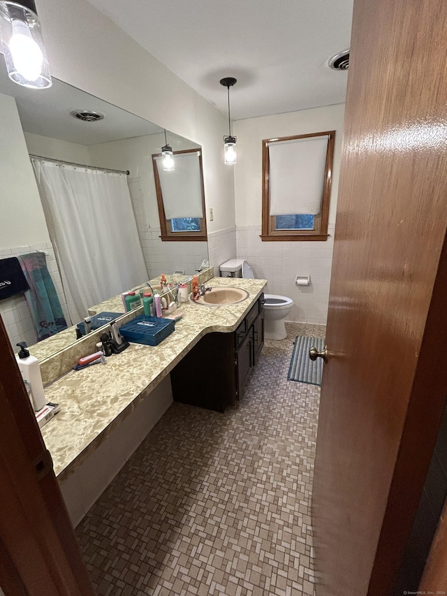 bathroom with vanity, toilet, and tile walls