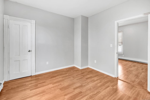 empty room with a baseboard radiator and light hardwood / wood-style flooring