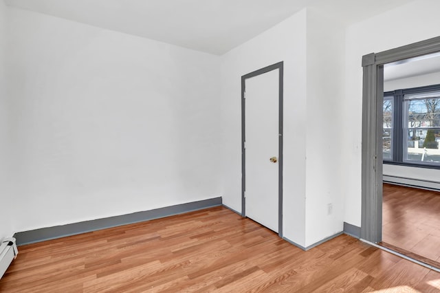 unfurnished bedroom with a closet, light hardwood / wood-style floors, and a baseboard radiator