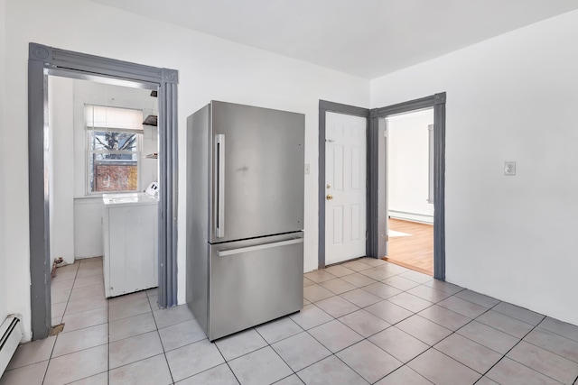 kitchen featuring stainless steel fridge, light tile patterned floors, washer / clothes dryer, and a baseboard radiator