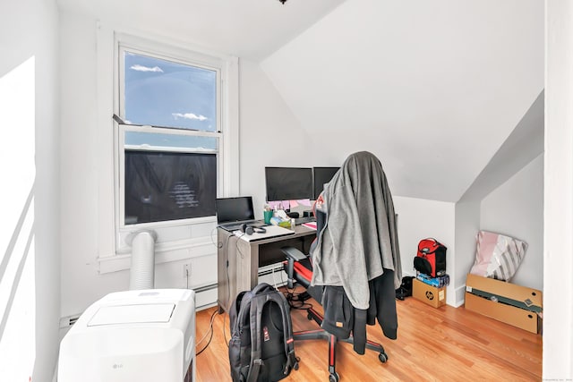 office area featuring light wood-type flooring, vaulted ceiling, and a baseboard heating unit