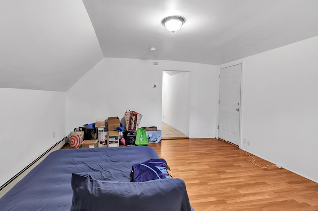 bedroom with lofted ceiling, light wood-type flooring, and a baseboard heating unit