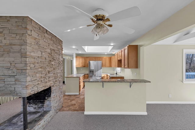 kitchen with carpet, a kitchen breakfast bar, stainless steel refrigerator with ice dispenser, a skylight, and kitchen peninsula