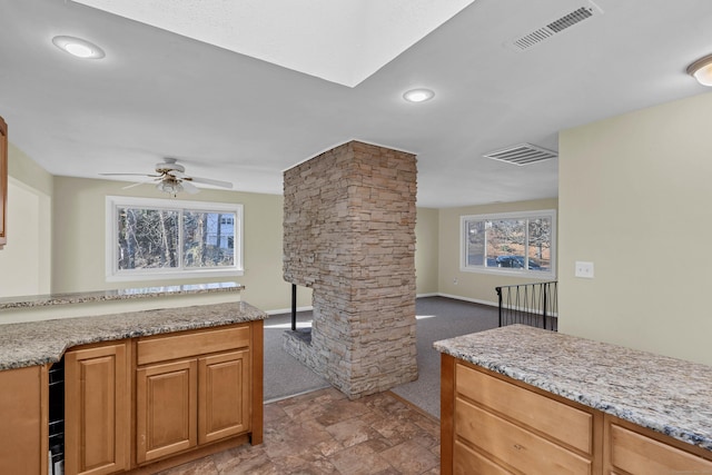 kitchen with decorative columns, a wealth of natural light, ceiling fan, and light stone countertops