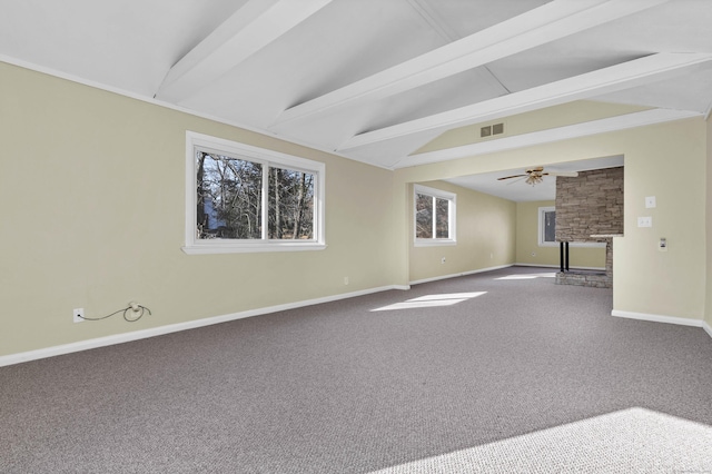 carpeted empty room featuring ceiling fan, a fireplace, and lofted ceiling with beams