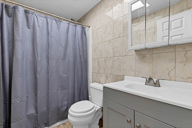 bathroom with vanity, curtained shower, toilet, and tile walls