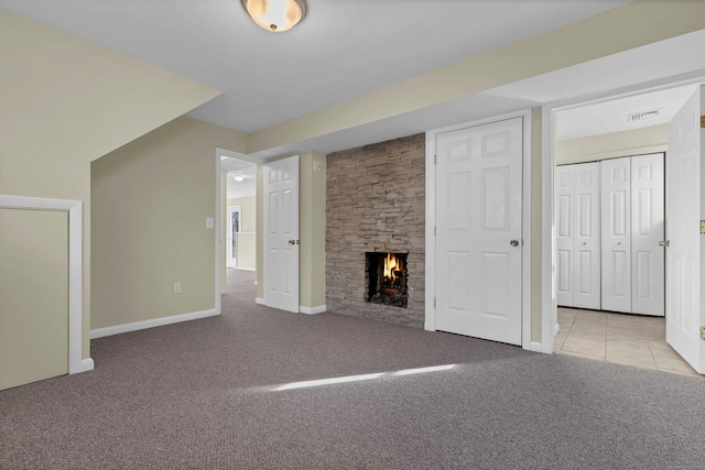 additional living space featuring a stone fireplace and light carpet