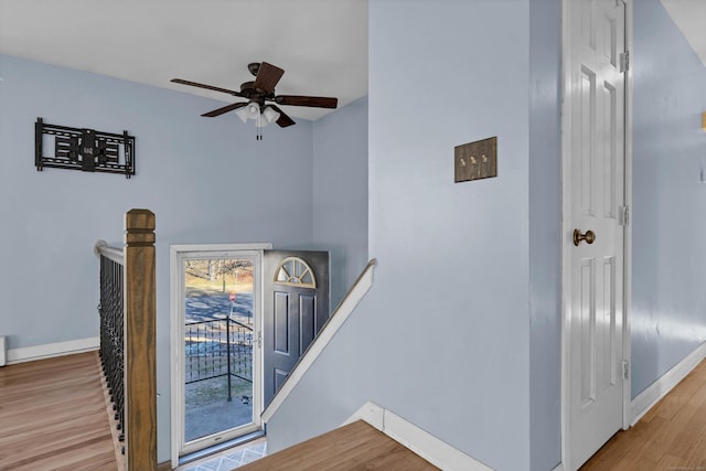 stairway with ceiling fan and wood-type flooring