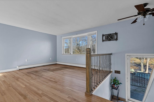 empty room with light hardwood / wood-style flooring, ceiling fan, and a baseboard heating unit