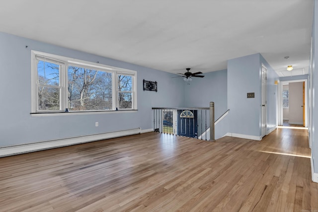 unfurnished living room featuring light hardwood / wood-style flooring, baseboard heating, and ceiling fan