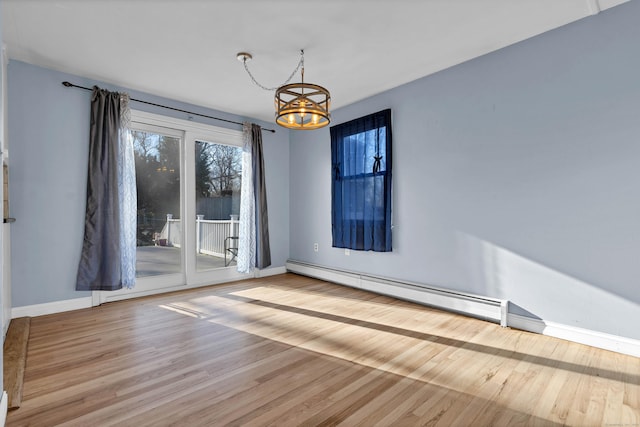 spare room featuring light hardwood / wood-style flooring, a baseboard heating unit, and a notable chandelier