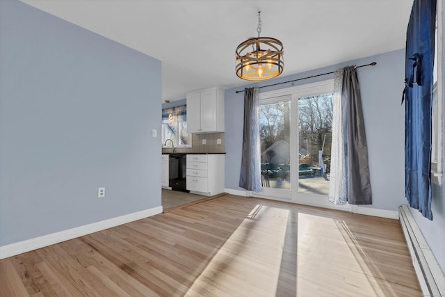 unfurnished dining area featuring sink, an inviting chandelier, light wood-type flooring, and a baseboard heating unit