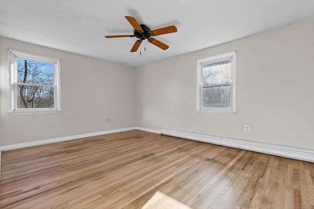 unfurnished room featuring baseboard heating, a wealth of natural light, ceiling fan, and light wood-type flooring