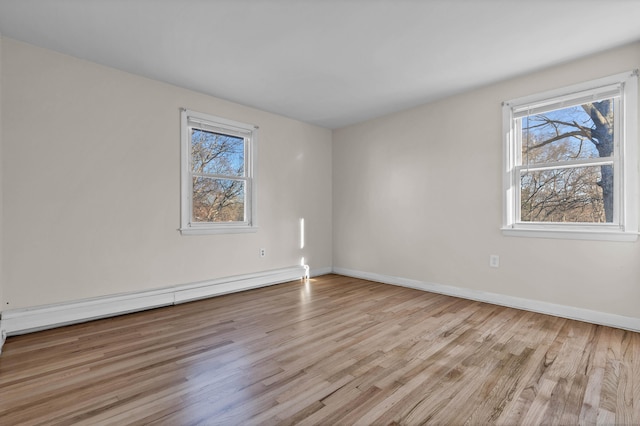 unfurnished room with light hardwood / wood-style floors, baseboard heating, and a healthy amount of sunlight