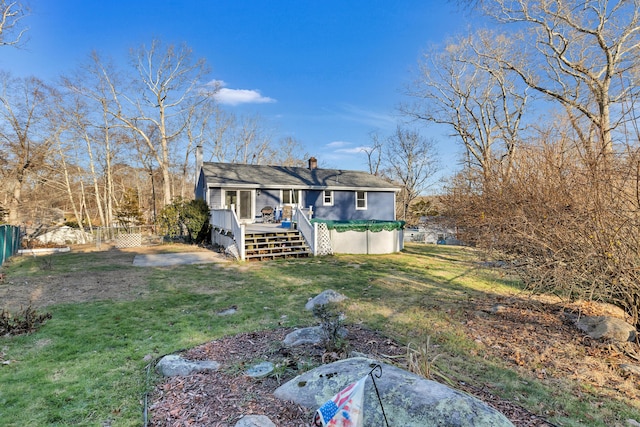 back of property with a wooden deck and a lawn