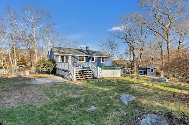 rear view of property with a lawn, a pool side deck, and an outdoor structure