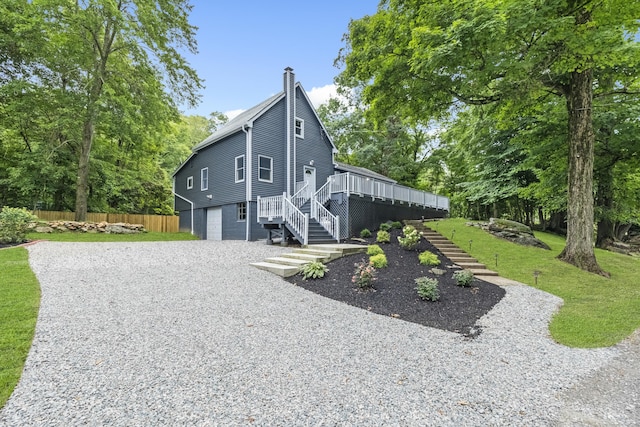 view of home's exterior featuring a wooden deck, a garage, and a lawn