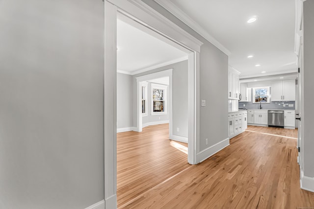 hallway featuring sink, crown molding, and light hardwood / wood-style flooring