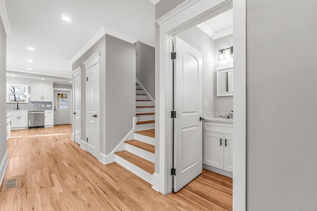 stairway with hardwood / wood-style flooring, crown molding, and sink