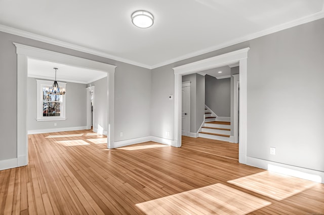 spare room with hardwood / wood-style flooring, crown molding, and a chandelier