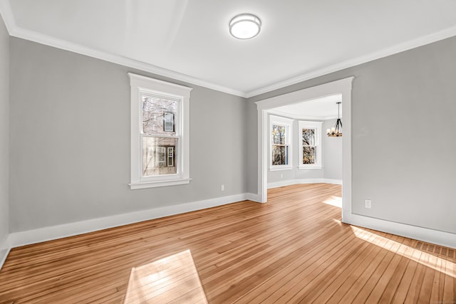 spare room featuring crown molding, light hardwood / wood-style floors, and a notable chandelier