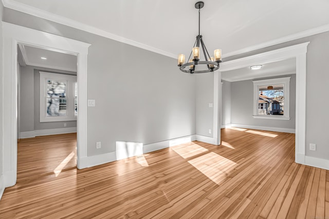 unfurnished dining area featuring light wood-type flooring, crown molding, and a chandelier