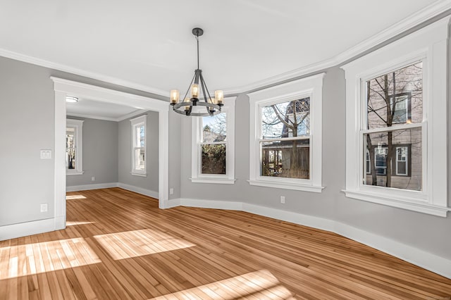 unfurnished dining area with crown molding, light hardwood / wood-style flooring, and a chandelier