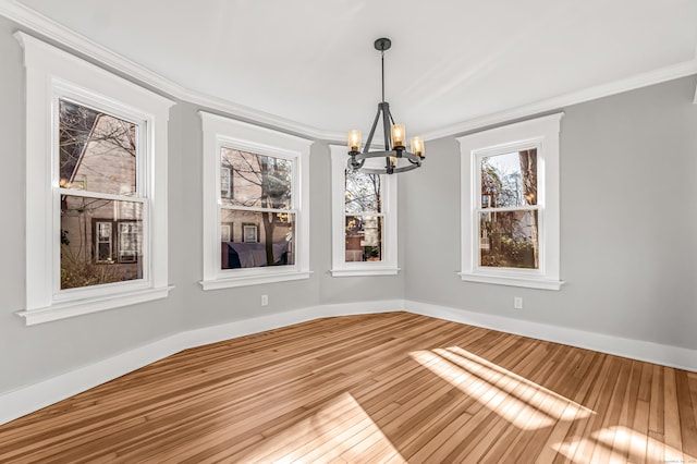 unfurnished dining area with hardwood / wood-style floors, an inviting chandelier, and crown molding