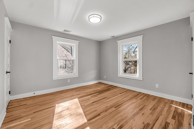 empty room featuring a healthy amount of sunlight and light hardwood / wood-style floors