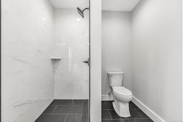 bathroom with tile patterned flooring, a tile shower, and toilet