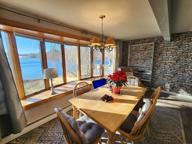 dining space with a water view, an inviting chandelier, plenty of natural light, and hardwood / wood-style flooring