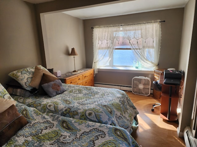 bedroom with hardwood / wood-style floors and baseboard heating