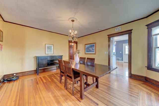 dining area with a notable chandelier, light wood-type flooring, and crown molding