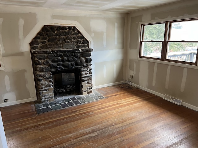 unfurnished living room featuring a stone fireplace and hardwood / wood-style floors