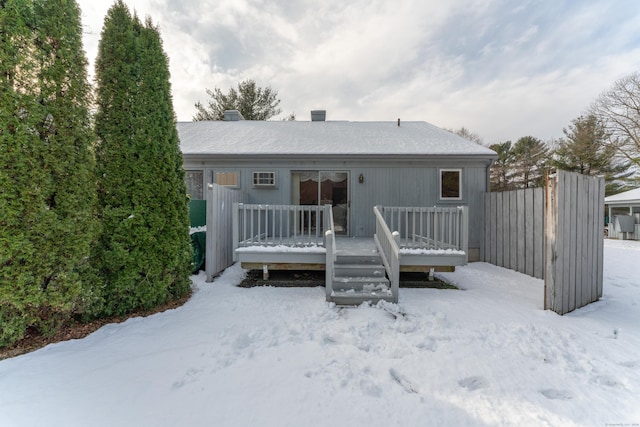 snow covered rear of property with a deck