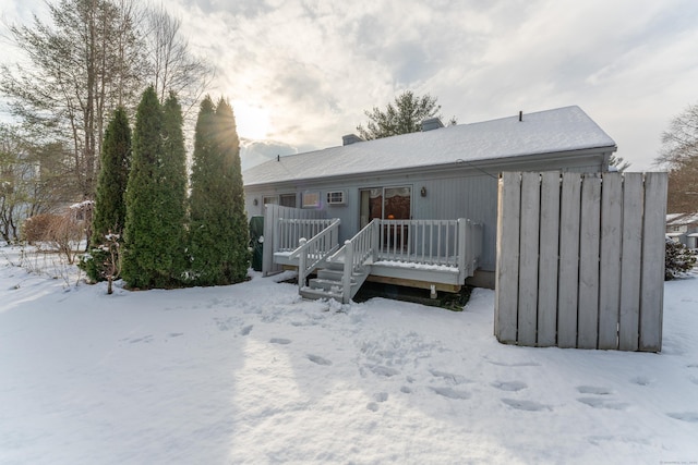 snow covered back of property with a deck