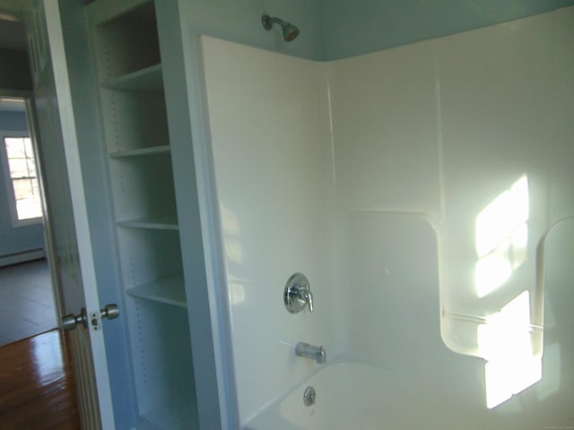 bathroom with bathtub / shower combination, built in features, and baseboard heating