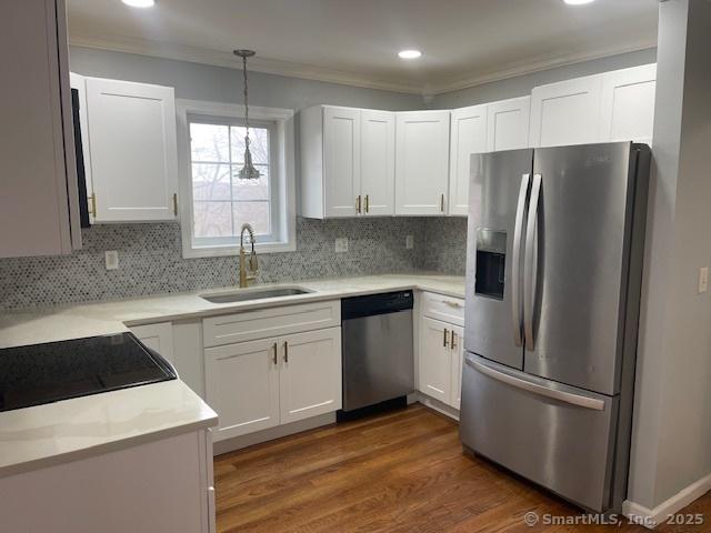 kitchen featuring sink, stainless steel appliances, backsplash, decorative light fixtures, and white cabinets