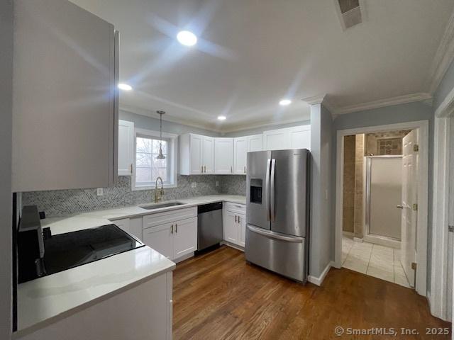 kitchen featuring dark hardwood / wood-style flooring, stainless steel appliances, sink, white cabinets, and hanging light fixtures