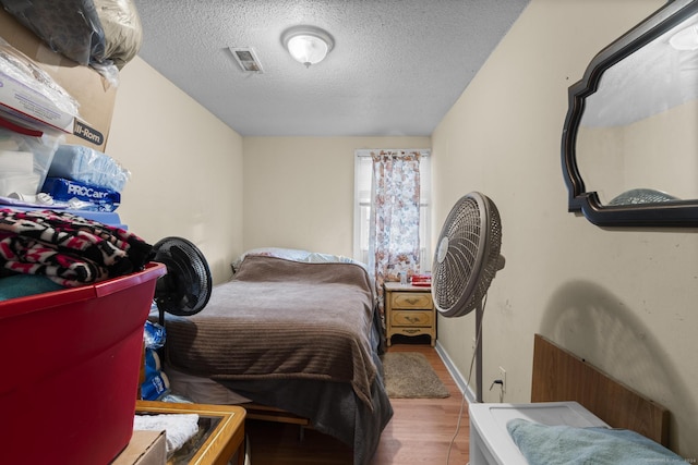 bedroom with a textured ceiling and light hardwood / wood-style flooring