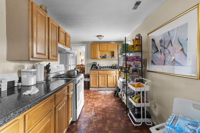 kitchen featuring range with gas stovetop, dark parquet flooring, and a textured ceiling