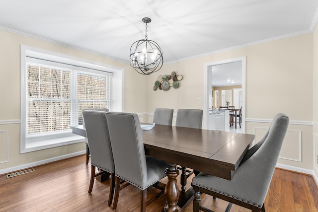 dining area with crown molding, an inviting chandelier, and wood-type flooring