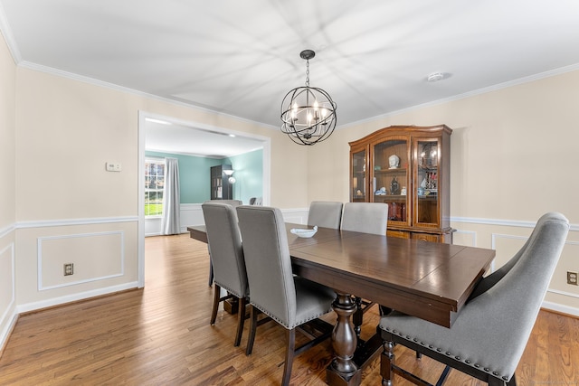 dining room with an inviting chandelier, hardwood / wood-style flooring, and crown molding